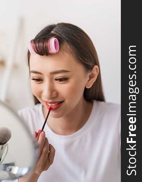 Asian woman beauty blogger,vlogger applying lipstick to her mouth doing cosmetic makeup tutorial.