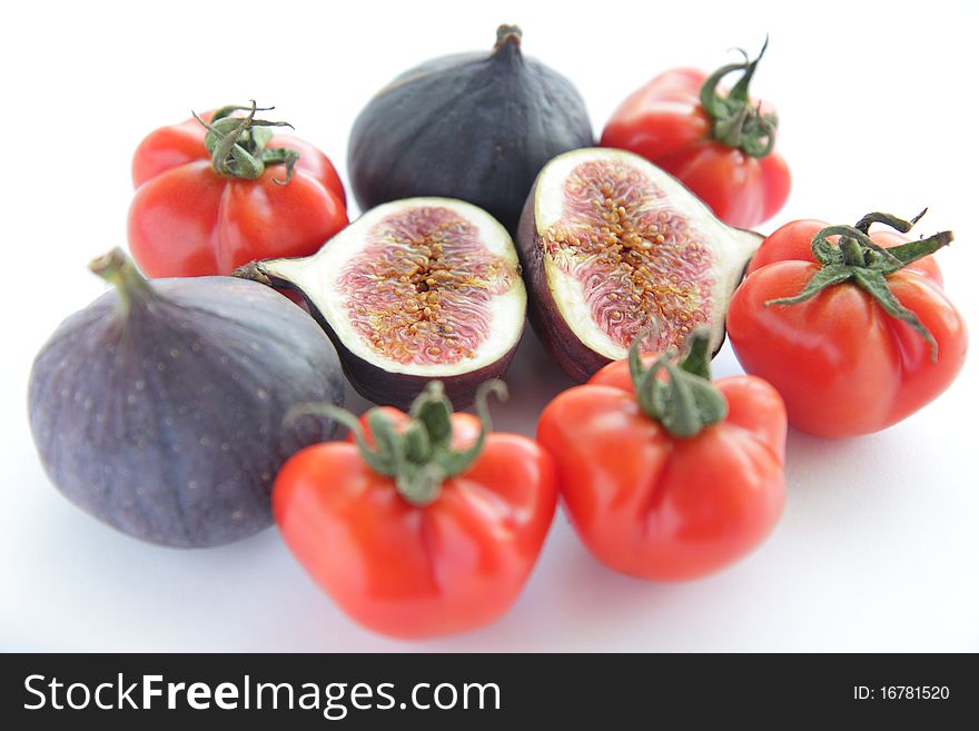 Ingredients for salad with fresh figs and tomatoes on white background. Ingredients for salad with fresh figs and tomatoes on white background