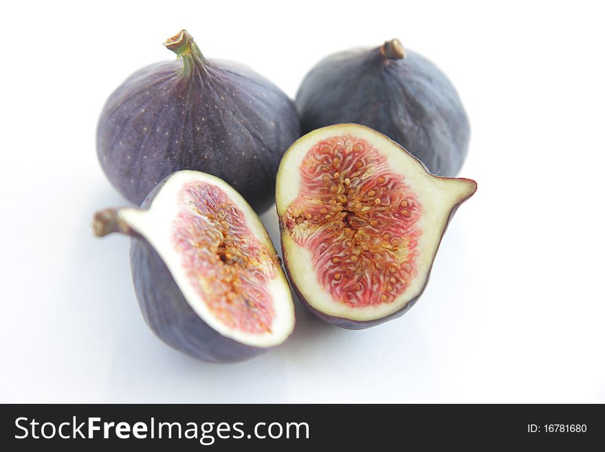 Two fresh whole figs and one cut in two halves fig on white background. Two fresh whole figs and one cut in two halves fig on white background