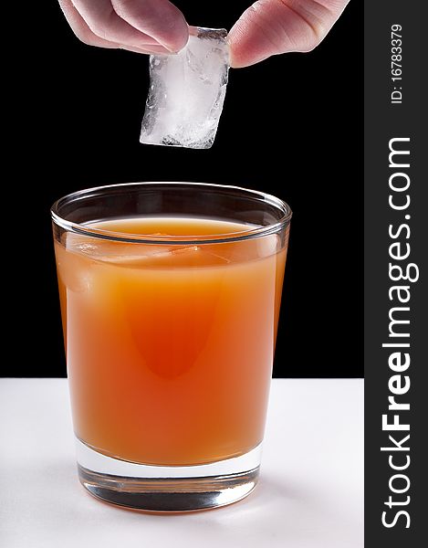 Grapefruit juce and ice cubes over black and white background. Grapefruit juce and ice cubes over black and white background