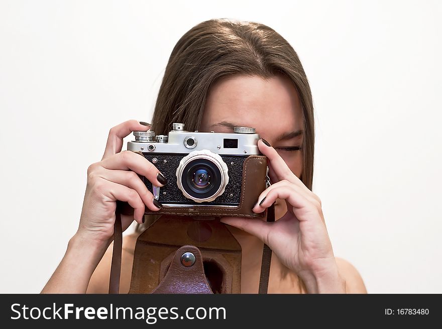 Young woman looks at an old film camera. Studio shot on white background. Young woman looks at an old film camera. Studio shot on white background.