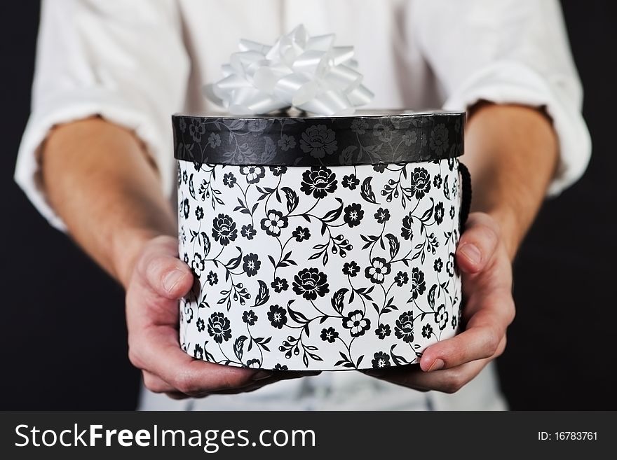 Male adult holding a round black and white decorated gift box with ribbon. Male adult holding a round black and white decorated gift box with ribbon.