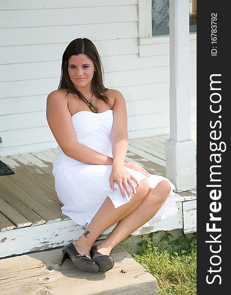 Girl sitting on porch in a white dress