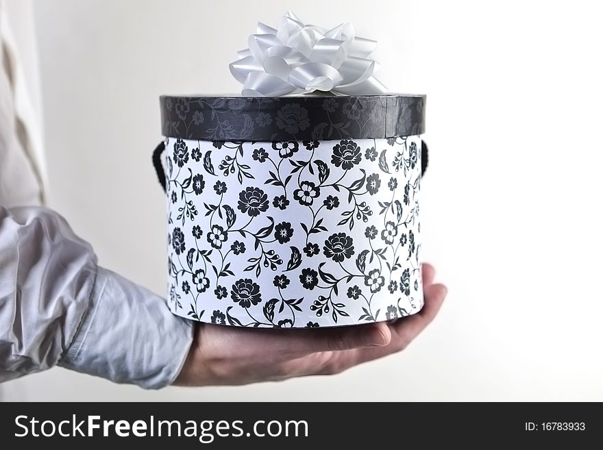 Male hand holding a round decorated present with ribbon against white background. Male hand holding a round decorated present with ribbon against white background.