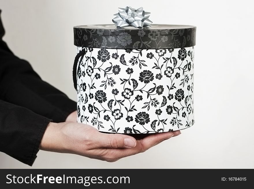 Female hand holding a decorated luxury gift box against white background. Female hand holding a decorated luxury gift box against white background.