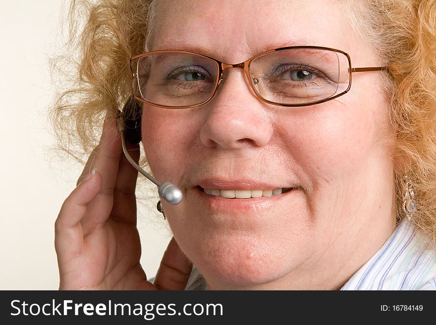 A mature woman taking a call on a hands free telephone headset. A mature woman taking a call on a hands free telephone headset