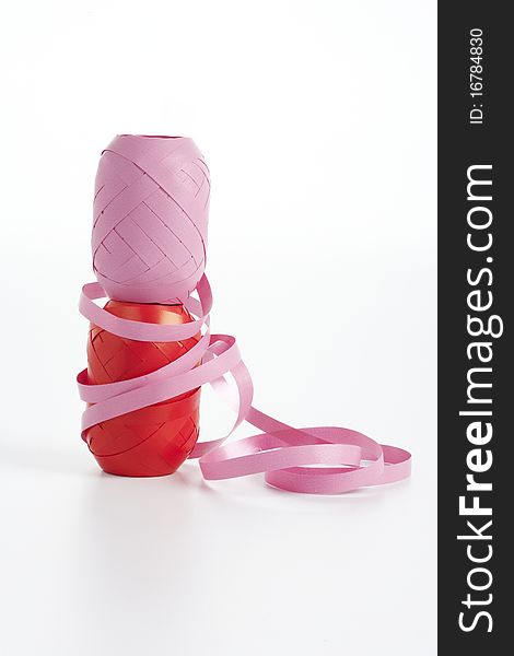 Pink and red spools of ribbon stacked on top of each other on a white background. Pink and red spools of ribbon stacked on top of each other on a white background