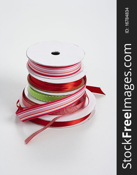 Five spools of red and green decorative ribbon from largest to smallest on top of each other. Five spools of red and green decorative ribbon from largest to smallest on top of each other.