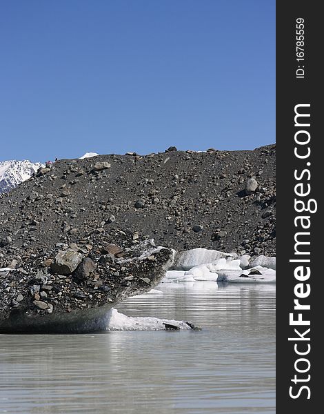 Icebergs floating in the Tasman lake with rocks/stones covering them. Icebergs floating in the Tasman lake with rocks/stones covering them.