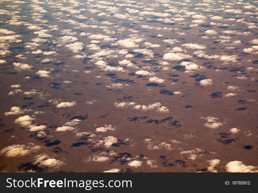 Popcorn clouds from the air over a orange desert landscape