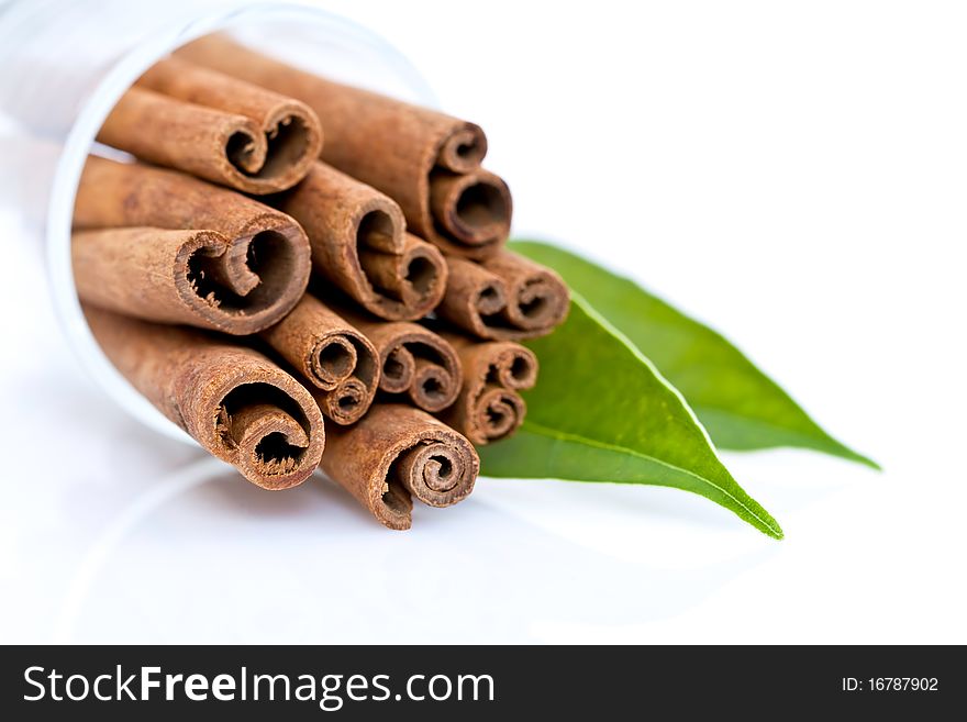 Cinnamon sticks with green leaves isolated on white.