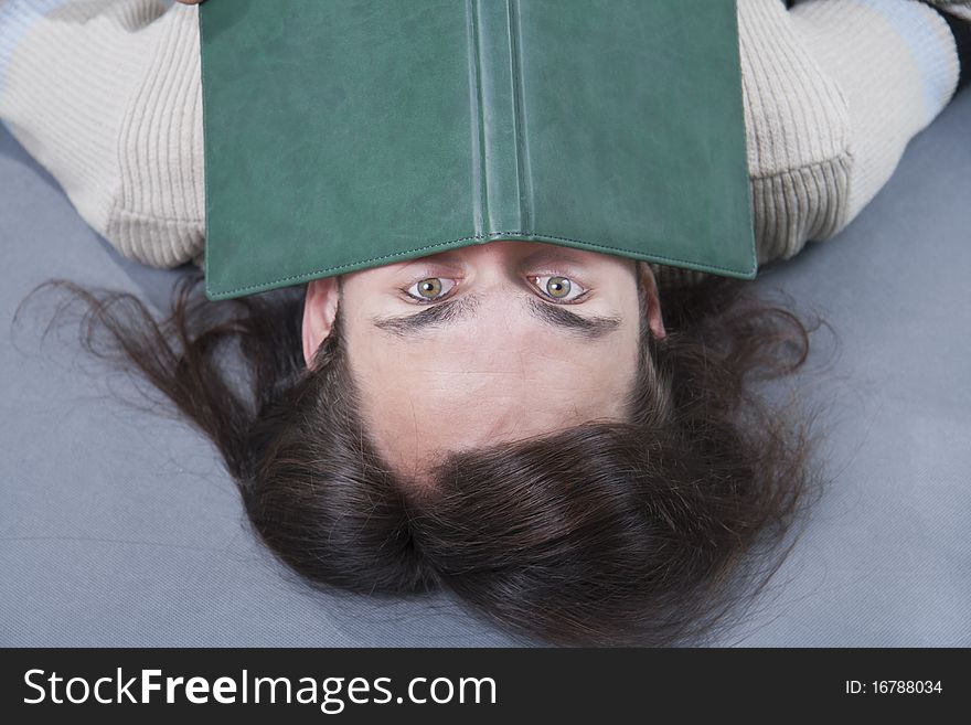 Long-haired man lies with book on his face. Long-haired man lies with book on his face