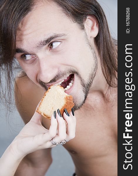 Young Man Eats A Cake From Female Hands