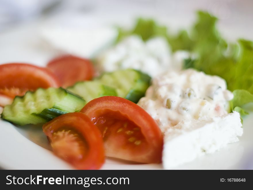 Salad , several kinds mixed in one plate with lettuce, tomatoes, cucumber and cheese on served decorated table background