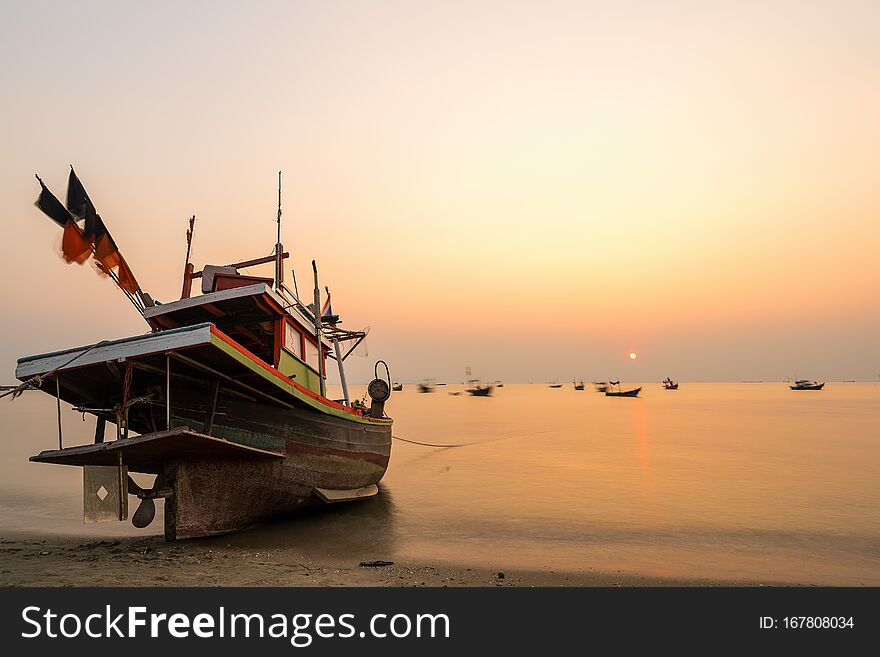 Beautiful seascape sunset with golden sunshine and fishing boat at the beach with copy space long exposure