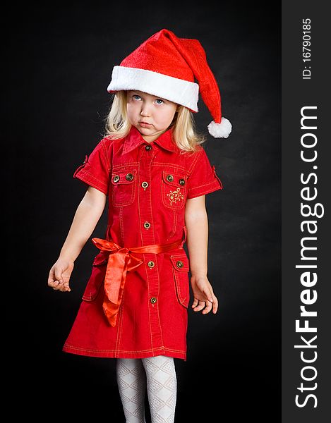 Haughty girl with demanding pout in red dress and santa cap. Haughty girl with demanding pout in red dress and santa cap