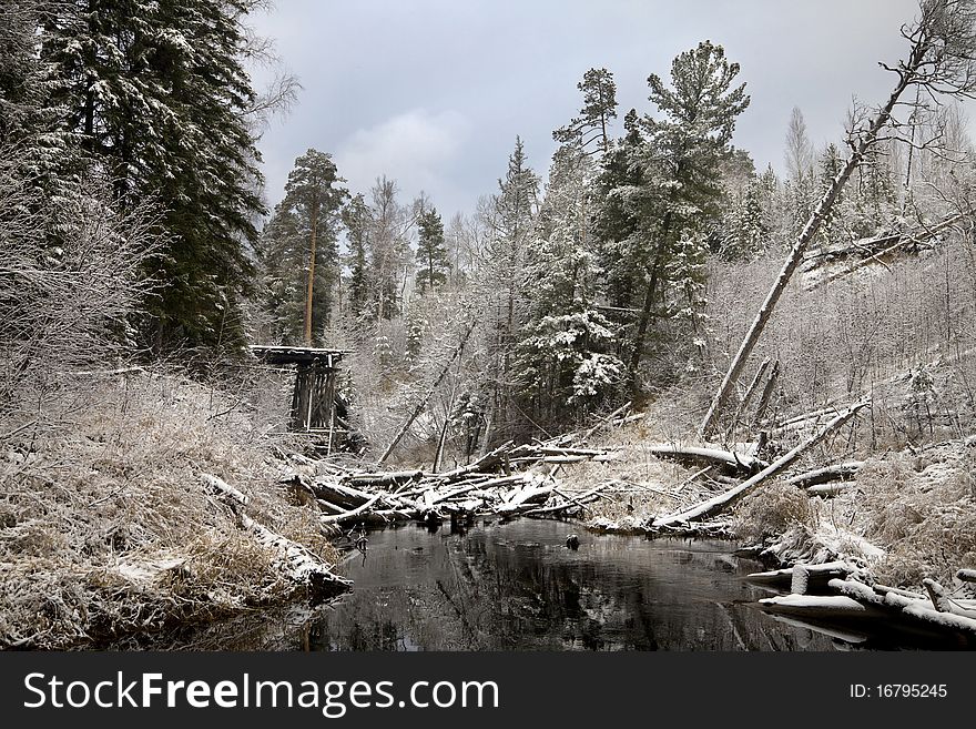Old wooden bridge over the river in coniferous forest after first snow fall. Old wooden bridge over the river in coniferous forest after first snow fall.
