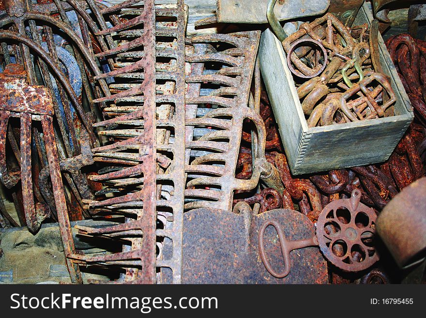 Assortment of rusted hand tools including rakes, pitchforks, and chain. Assortment of rusted hand tools including rakes, pitchforks, and chain