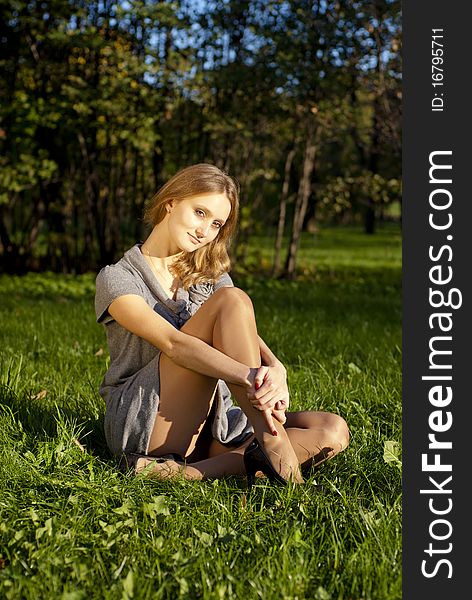 Portrait of a beautiful young woman in park sitting on the grass. Portrait of a beautiful young woman in park sitting on the grass