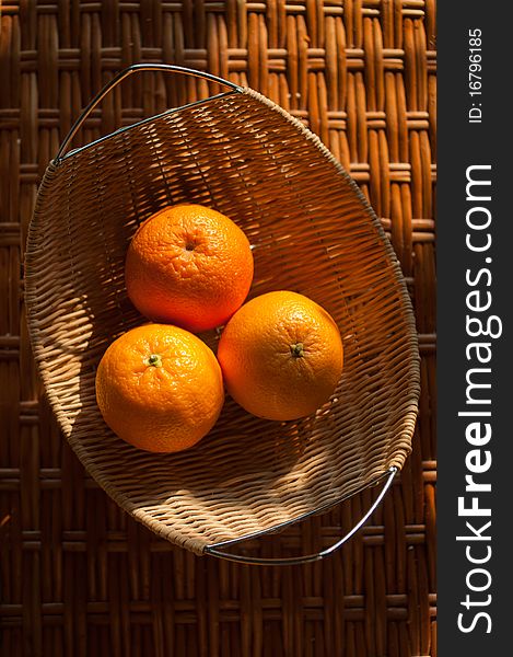 Three oranges in the wattled bowl on the table