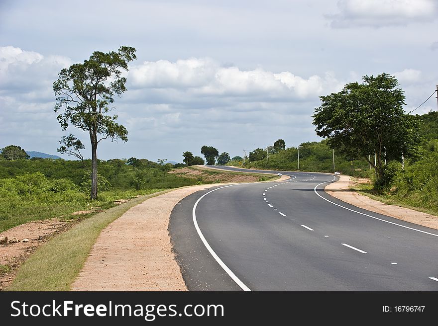 S shaped road running to the horizon with the clouds over it