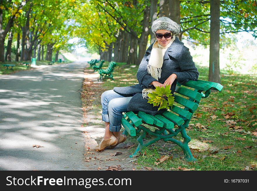 Pretty young woman resting on a bench in autumn park