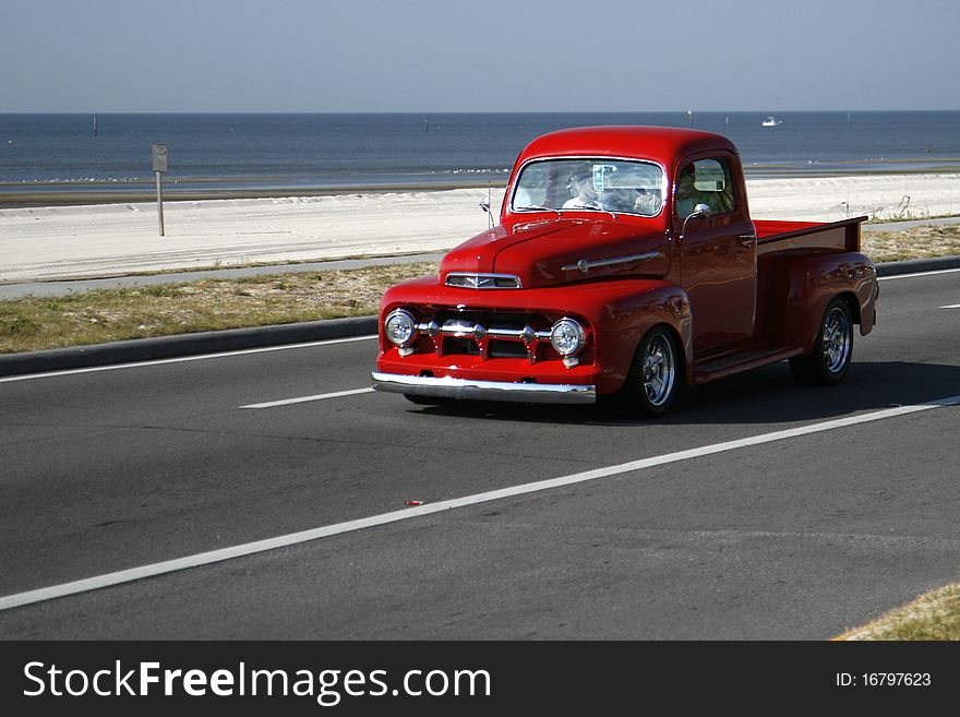 Old red ford pickup truck driving on beach highway. Old red ford pickup truck driving on beach highway.