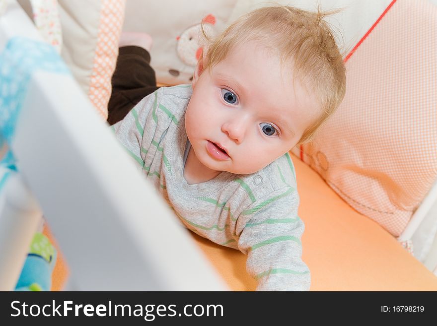 Baby lying in the latticed bedsted and look around. Baby lying in the latticed bedsted and look around