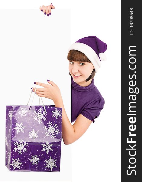 Smiling woman with shopping bag in Santa hat holding blank billboard, isolated on white. Smiling woman with shopping bag in Santa hat holding blank billboard, isolated on white