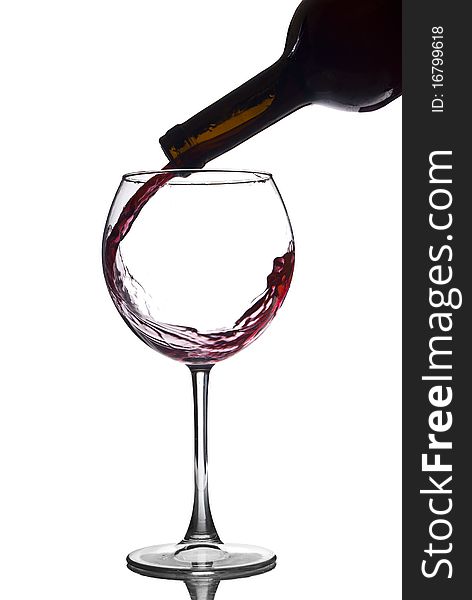 Pouring red wine in a glass of white background