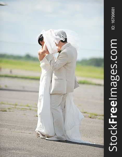 Groom and the bride in a white dress dance on an airfield. Groom and the bride in a white dress dance on an airfield