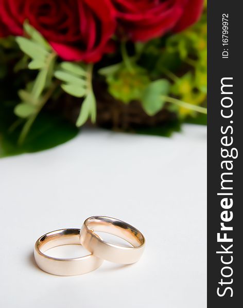 Closeup of two golden wedding rings with red roses in the background. Closeup of two golden wedding rings with red roses in the background