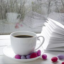 Cozy Concept: A White Cup Of Coffee Stands On A White Wooden Table Next To A White Open Book And Colorful Candy Against The Royalty Free Stock Images