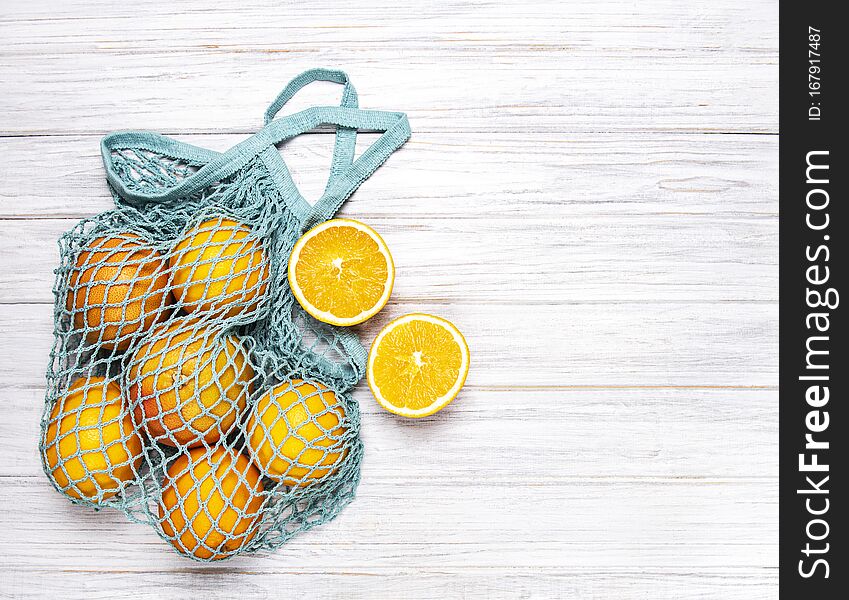 Mesh shopping bag with organic  oranges on white wooden background. Flat lay, top view. Zero waste, plastic free concept. Healthy clean eating diet and detox. Summer fruits. Mesh shopping bag with organic  oranges on white wooden background. Flat lay, top view. Zero waste, plastic free concept. Healthy clean eating diet and detox. Summer fruits