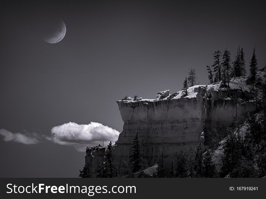 Black and white, fine art scene of a half moon setting at night over a rock cliff in Bryce Canyon National Park, Utah. Black and white, fine art scene of a half moon setting at night over a rock cliff in Bryce Canyon National Park, Utah.