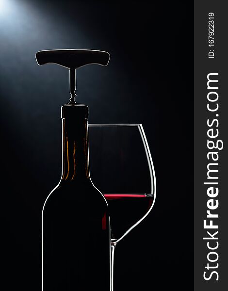 Bottle with corkscrew and glass of red wine