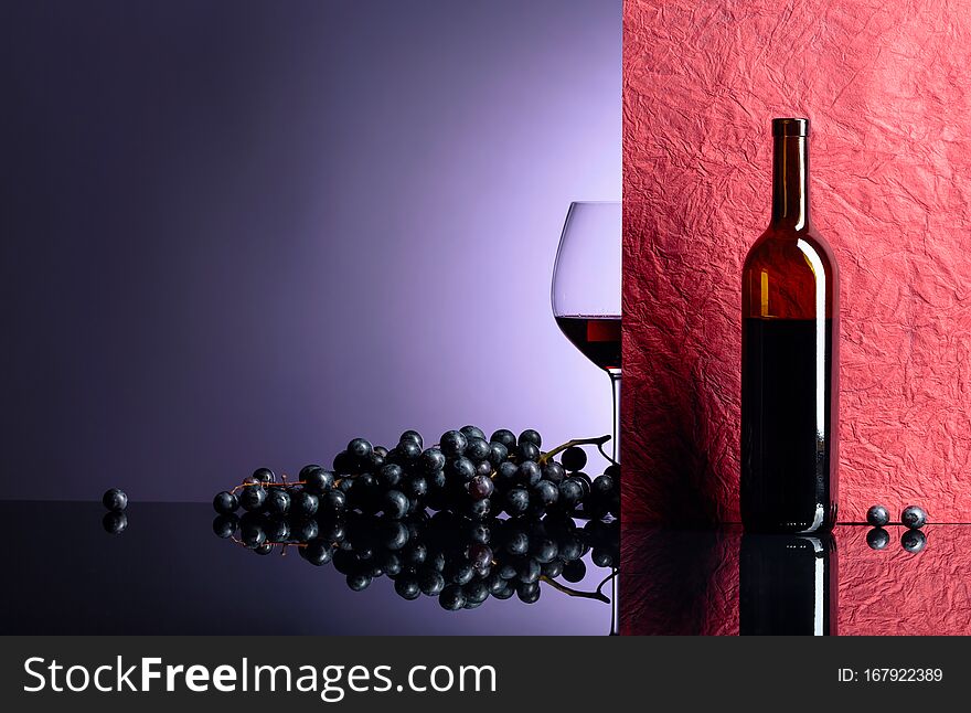 Bottle and glass of red wine on a black table. Free space for your text. Focus on foreground