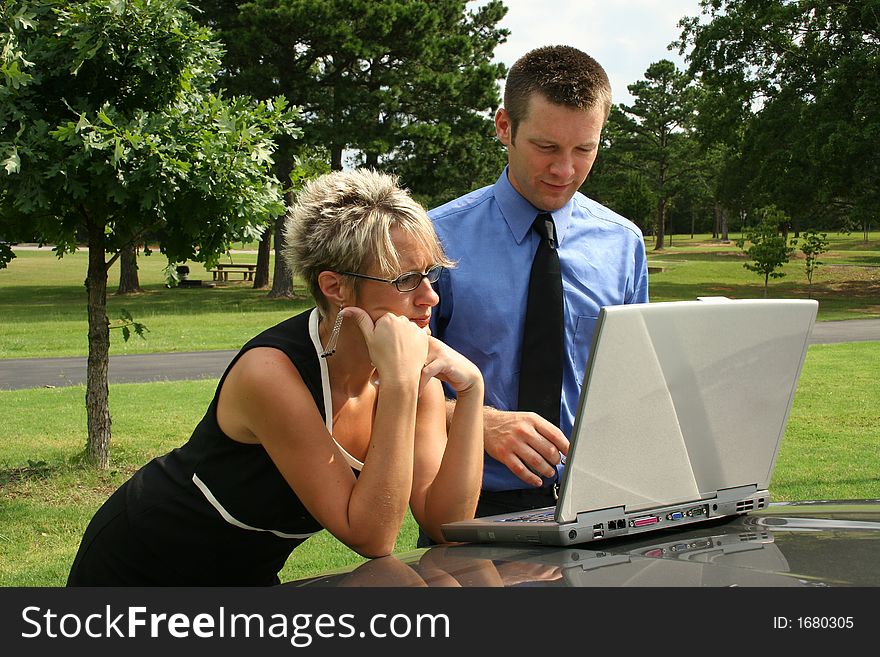 Man and woman working outdoors on computer. Man and woman working outdoors on computer.