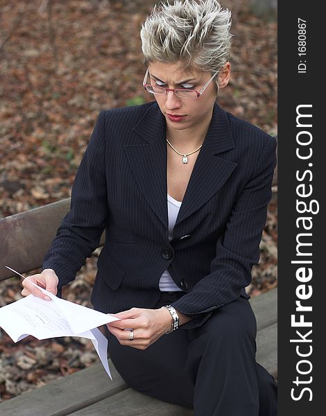 Business woman outdoor in a park reading mails and notebook