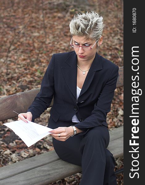 Business woman outdoor in a park reading mails and notebook