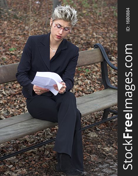 Business woman outdoor in a park reading mails and notebook