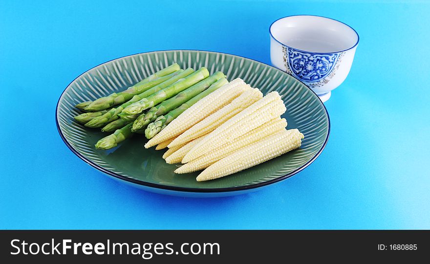 Fresh asparagus shoots and corn on a plate