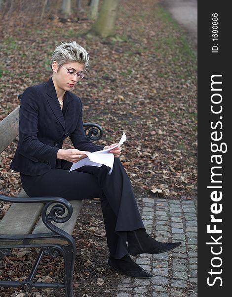 Business woman outdooring a park reading mails and notebook. Business woman outdooring a park reading mails and notebook