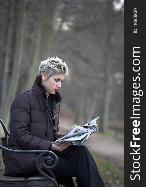 Business woman outdoor in a park reading a magazine