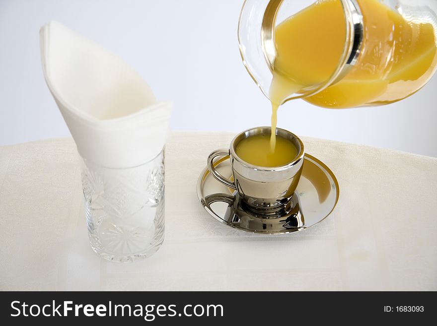 Orange juice is being poured into espresso cup. Orange juice is being poured into espresso cup