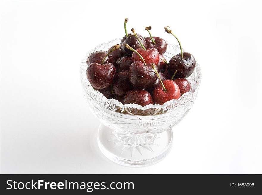 Fresh red cherries in a crystal bowl on white background. Fresh red cherries in a crystal bowl on white background