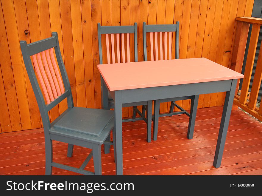 A table and chairs setting on a wooden deck. Photographer: Crystal Venus. A table and chairs setting on a wooden deck. Photographer: Crystal Venus.