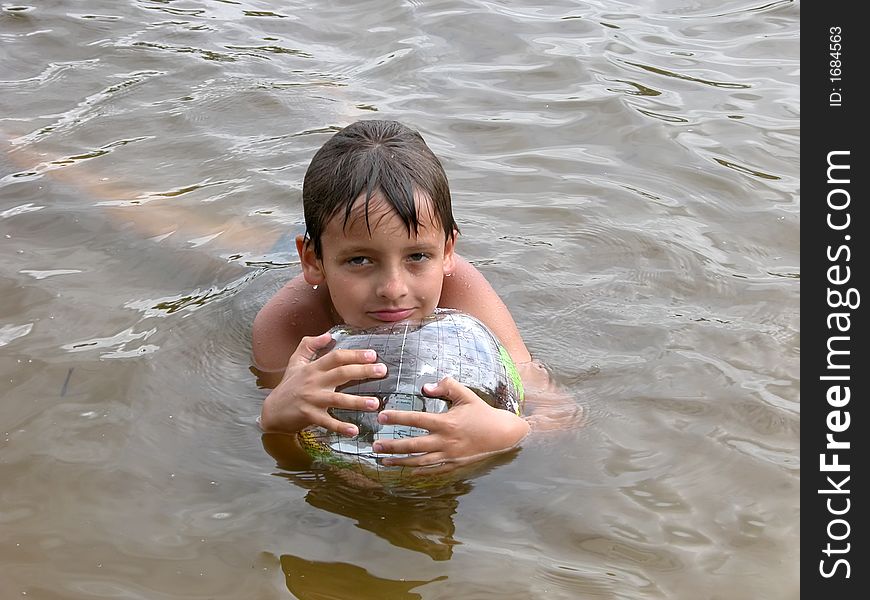 Boy with plastic transparent toy ball globe in water. Boy with plastic transparent toy ball globe in water