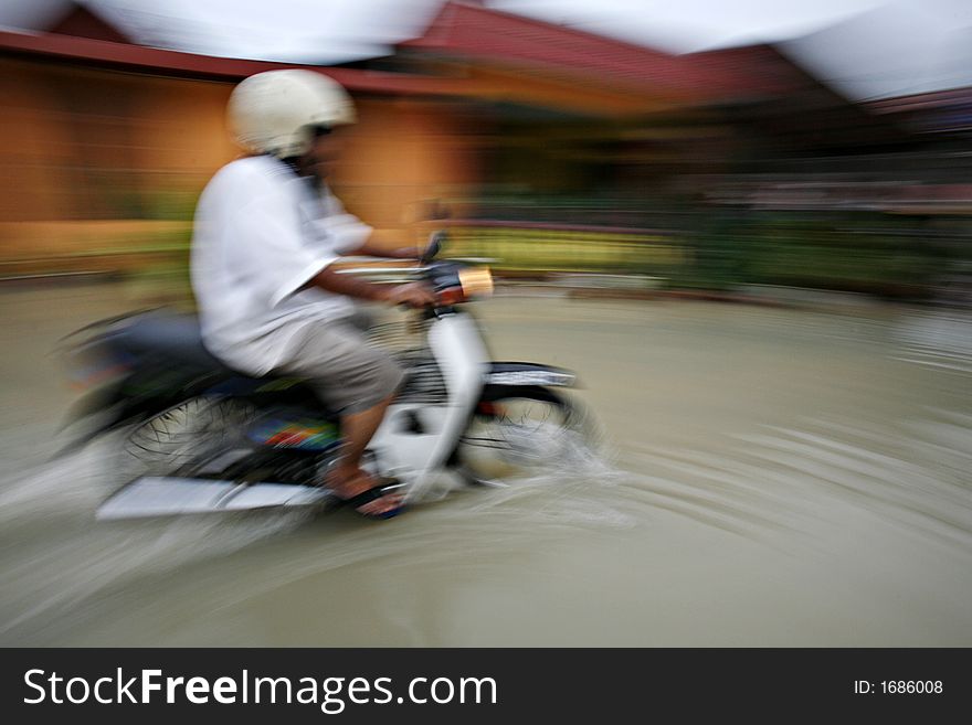 A man rides a motorcycle through a flooding street, motion blur. A man rides a motorcycle through a flooding street, motion blur