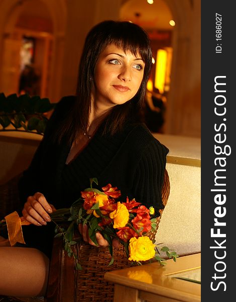 Stylish girl with a bunch of flowers sitting on a sofa. Stylish girl with a bunch of flowers sitting on a sofa